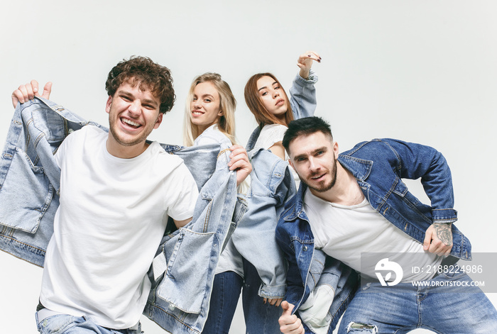 Group of smiling friends in fashionable jeans. The young men and woman posing at studio. The fashion, people, happy, lifestyle, clothes concept