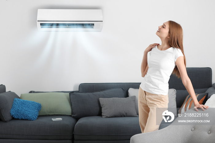 Young woman enjoying cool air flow from conditioner at home