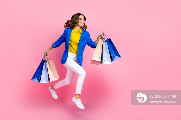 Full length profile portrait of crazy active person hold bags jumping hurry run empty space isolated on pink color background