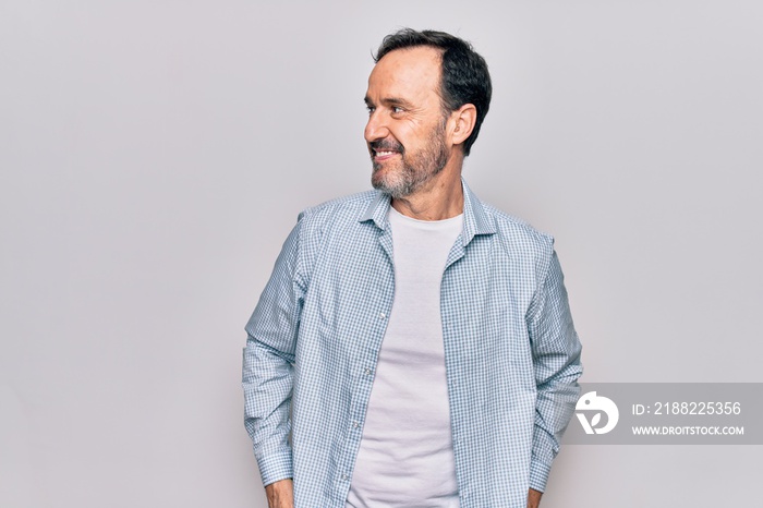 Middle age handsome man wearing casual denim shirt standing over isolated white background looking to side, relax profile pose with natural face and confident smile.