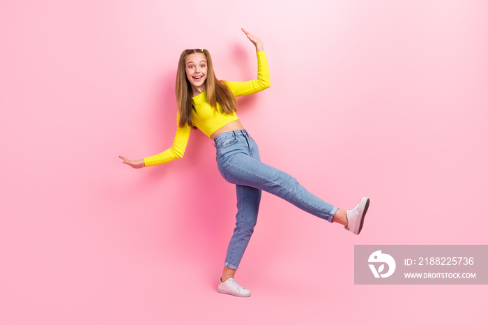 Full length photo of excited pretty schoolgirl wear yellow crop top walking having fun isolated pink color background