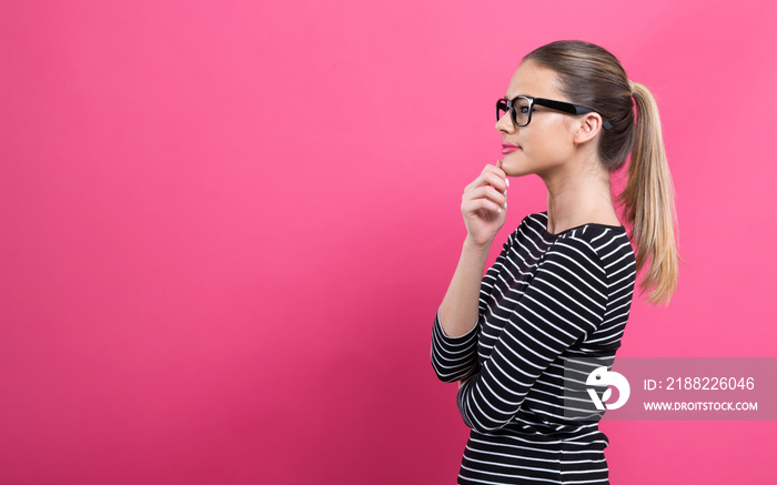 Young woman in a thoughtful pose on a pink background