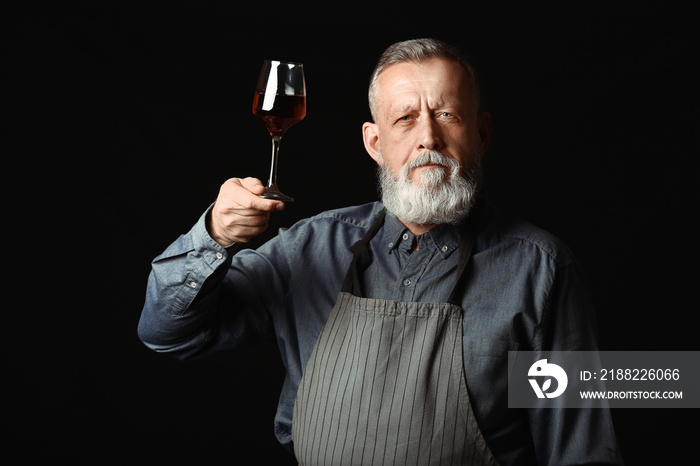 Portrait of mature sommelier on dark background