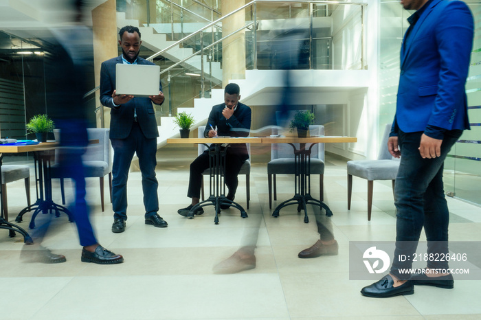 africa american business man working with laptop,blurred people walking next to him in big office