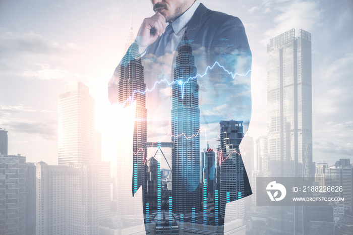 Thoughtful young european businessman in suit standing on abstract bright city background with forex chart and mockup place. Finance, trade and success concept. Double exposure.