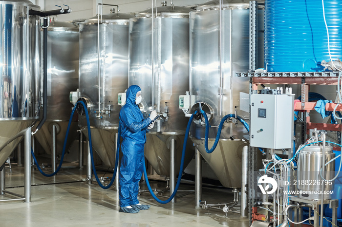 Worker in protective gear operating storage tanks