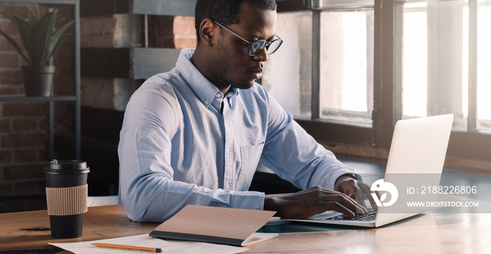 Modern african man using laptop in modern loft office