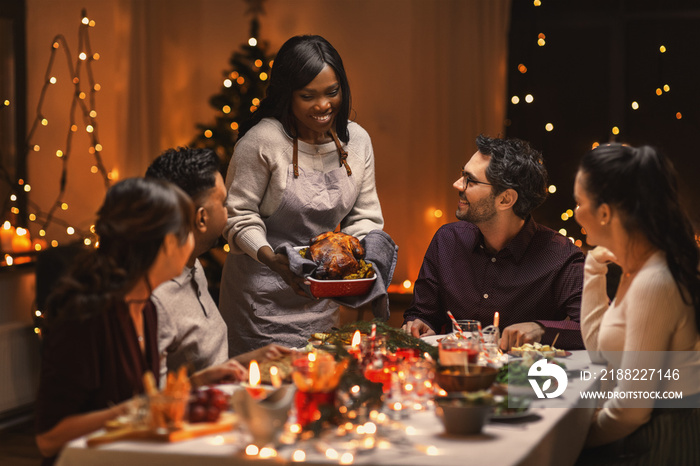 holidays and celebration concept - multiethnic group of happy friends having christmas dinner at home