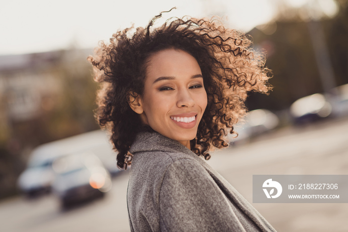 Profile portrait of pretty curly hairstyle dark skin person turn head camera toothy smile have good mood free time walking outdoors