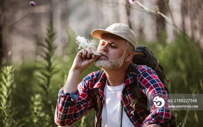 Bearded mature man smoking medical marijuana in nature.