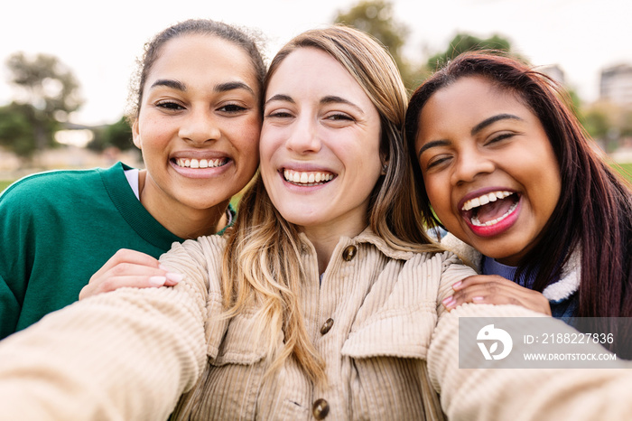 Young group of three diverse cheerful women taking selfie together outdoors. Female friendship lifestyle concept