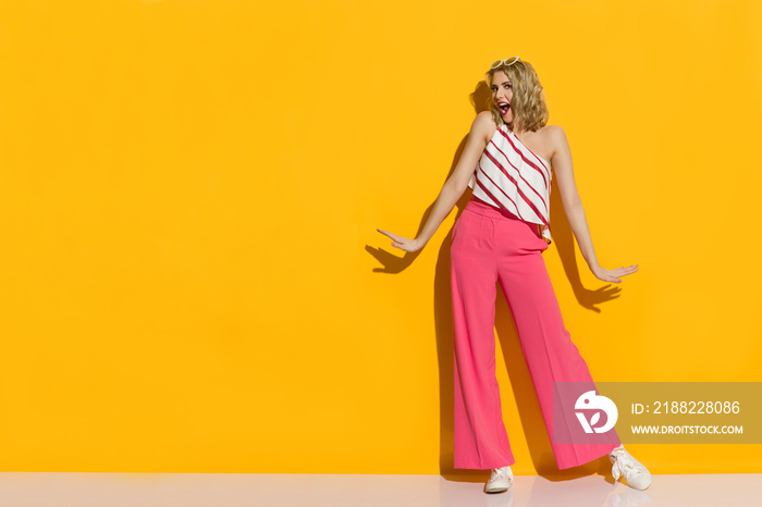 Stylish Young Woman In Pink Wide Leg Trousers Is Standing In The Sunlight And Shouting