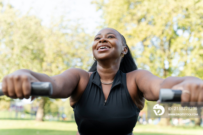 Smiling young woman exercising in outdoor gym