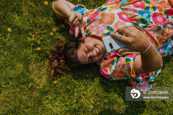 plus size woman lies on grass and takes a selfie