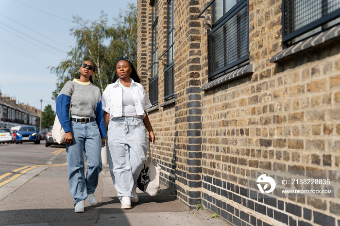 Young female couple holding hands in street