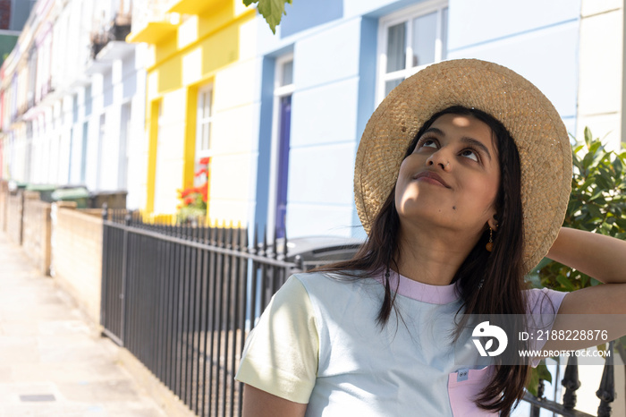 Smiling young woman in sun hat standing in street