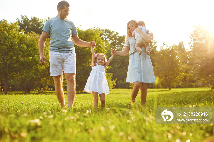 Happy family walking on the grass in the summer park. Children Protection Day.