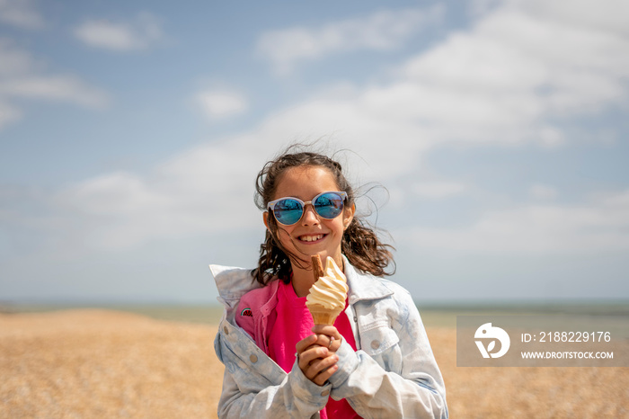 Portrait of smiling girl (8-9) eating ice cream on beach