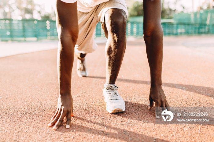 A young athletic African American stands at the start of the treadmill at the stadium