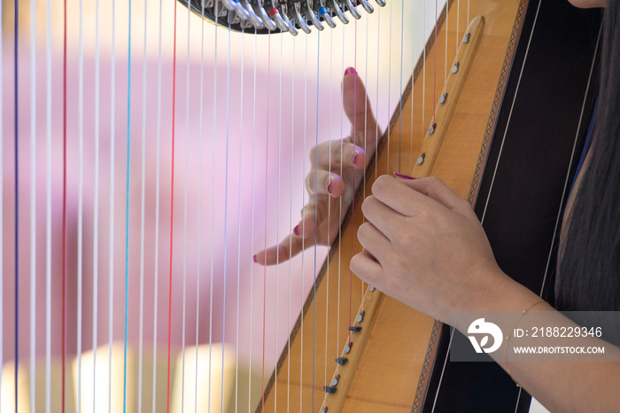 female fingers playing the harp