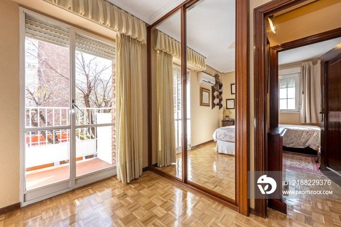 Wardrobe with sliding mirrored doors and exit window to the terrace with parquet floors