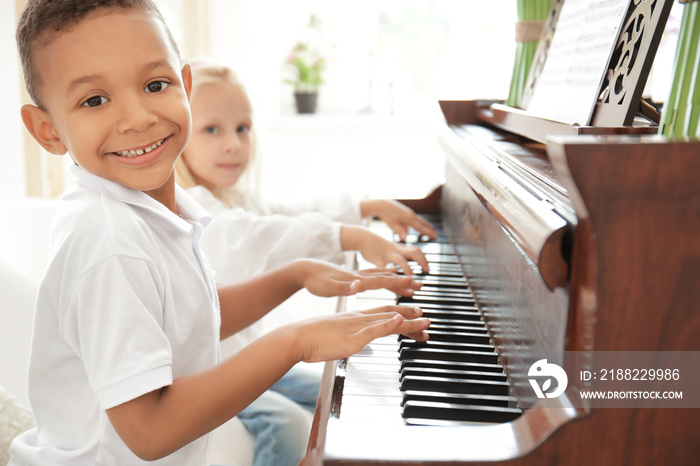 African-American boy with little girl playing piano indoors