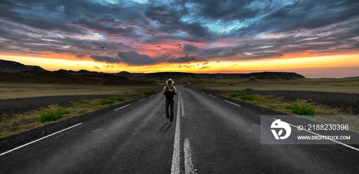 Man walking on the road and in the background a sunset