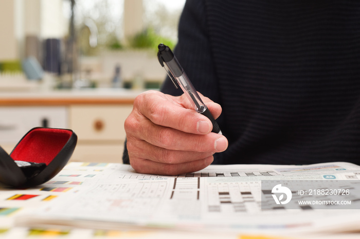 Mature man doing a crossword puzzle and relaxing at home during the day, indoor shot