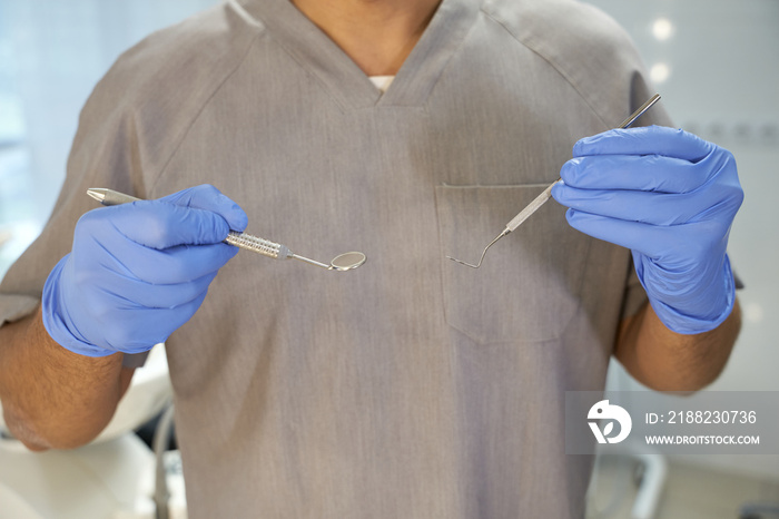 Profesional dental specialist posing with pick and dental mirror