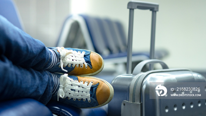 Feet and shoes of a young hipster passenger taking nap near the gate while waiting for connection or delayed flight