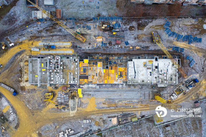 A construction site with yellow tower construction cranes - aerial top view - concept of housing construction. Concept Investments in Housing and Business Complexes.