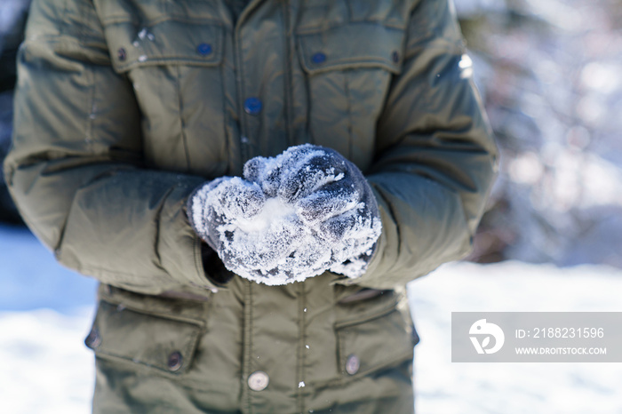 Man making snowballs in winter. Close up of male hands in snowy gloves. Playing in snow and having fun on nature. Family outdoors activities on Christmas holidays. Authentic lifestyle moment