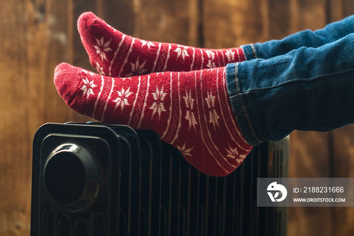 Women’s feet in Christmas, warm, winter socks on the heater. Keep warm in the winter, cold evenings. Heating season