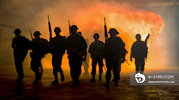 silhouette of unrecognized soldiers with rifle walk through smoke, yellow smoked background.