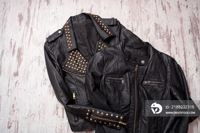 Fashionable concept. Two black leather jackets on a wooden background. Top view, space for text