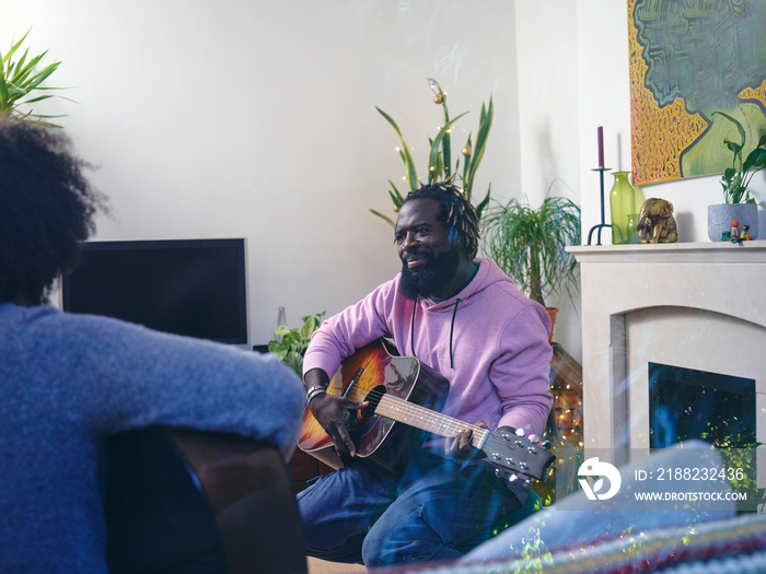 Couple playing acoustic guitars at home