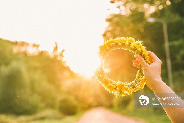 woman hand holding wreath of yellow dandelions