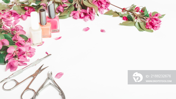 A set of manicure tools and accessories on a white background with flowers. Nail care. Flat lay. Copy space. Women’s Day. March 8