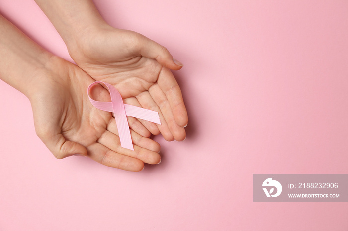 Female hands with pink ribbon on color background. Breast cancer awareness concept