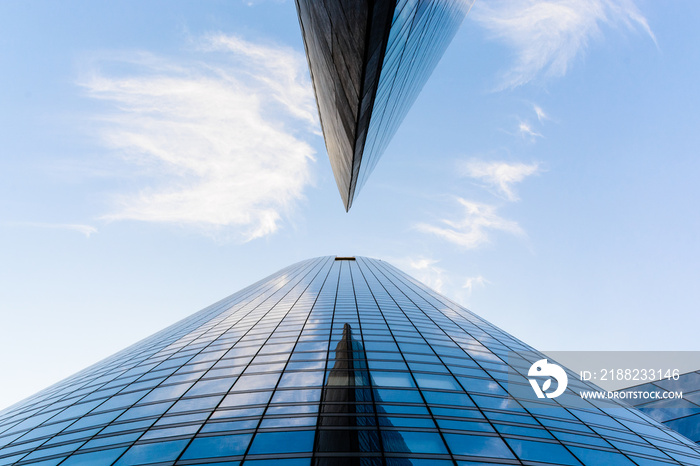 Low angle view of skyscrapers and glass buildings with blue sky in a geometric arrangement.