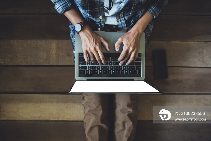 businessman in casual wear, blue plaid shirt. brown pants, green and sneakers sitting on wooden floor he using laptop  with blank screen working at home