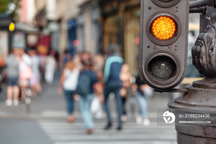 yellow signal of the traffic light with blurred pedestrian at the background