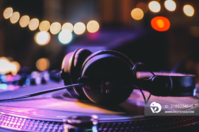 DJ headphones on a vinyl player in a dark nightclub, selective focus