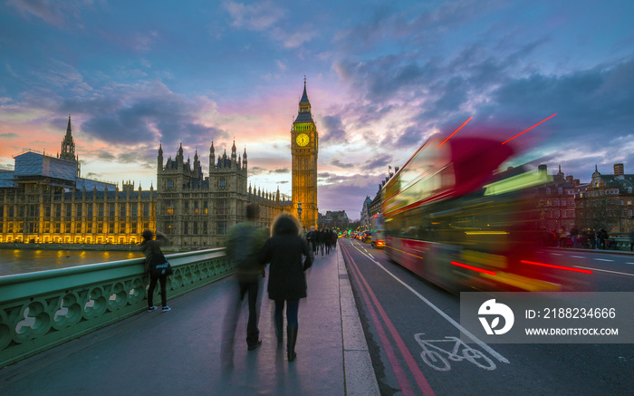 London, England - Iconic Red Double Decker Bus on the move on Westminster Bridge with Big Ben and Houses of Parliament at background. Sunset with beautiful colorful sky