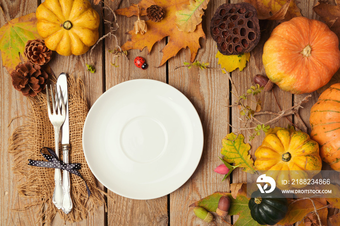 Autumn background with plate, fall leaves and pumpkin over wooden table. View from above