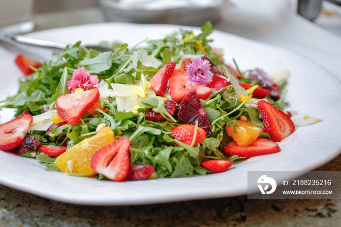 A view of an arugula salad, featuring chopped tropical fruit.