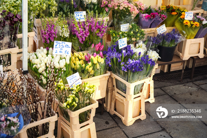 Various flowers on display at street flower stall in London market, Bouquets displayed inside plastic boxes