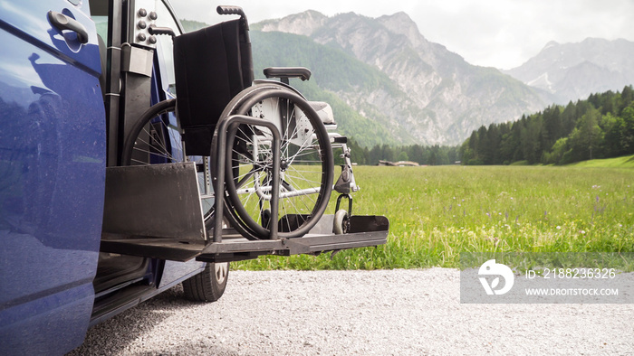 Photo of black electric lift specialized vehicle for people with disabilities. Empty wheelchair on a ramp with nature and mountains in the back