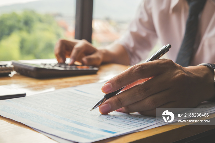 Close up hands businessman doing finances with using calculator and point to Market Graph in home office