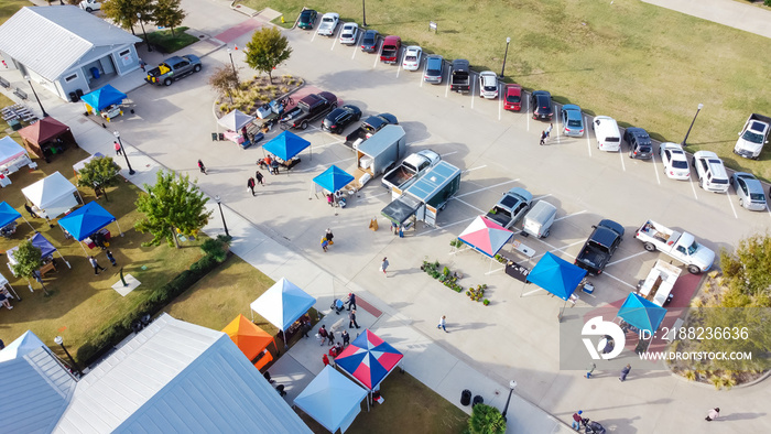 Aerial view busy parking lot near row of colorful tents with people shopping at farmer market near Dallas, Texas, USA